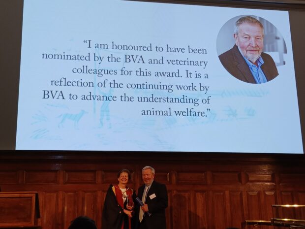 Collin Willson at the RCVS Awards Day. He is in front of a large screen that says "I am honoured to have been nominated by the BVA and veterinary colleagues for this award. It is a reflection of the continuing work by BVA to advance the understanding of animal welfare.