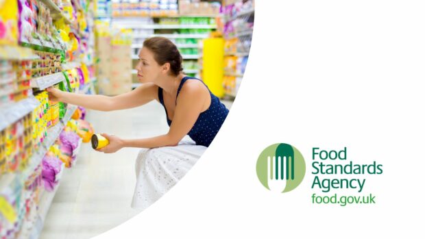 A woman crouching in a supermarket aisle. She has a yellow tin of food in her left hand and is reaching for another from a shelf. Food Standards Agency logo in bottom right.