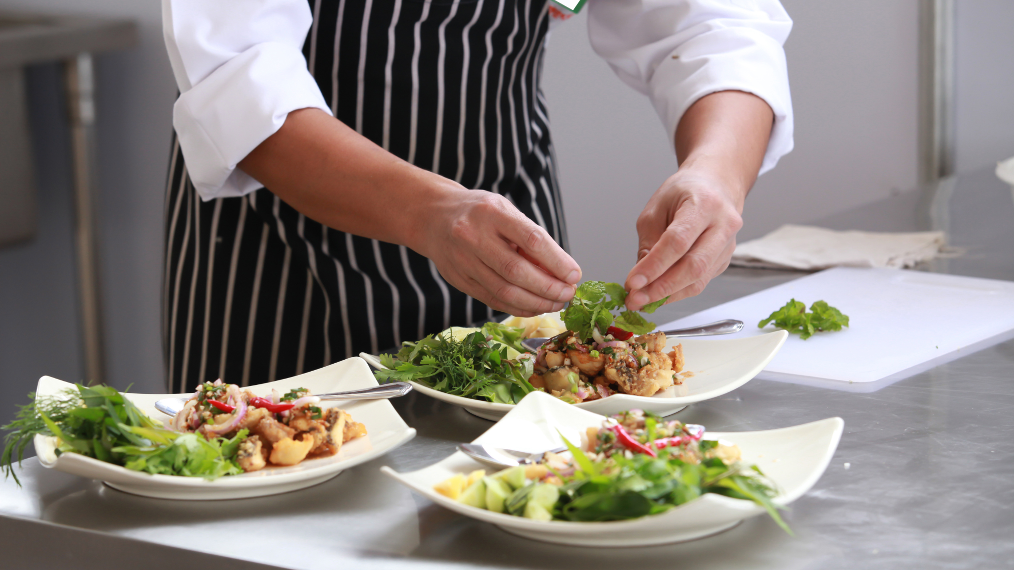 A person plating up meals in a restaurant kitchen