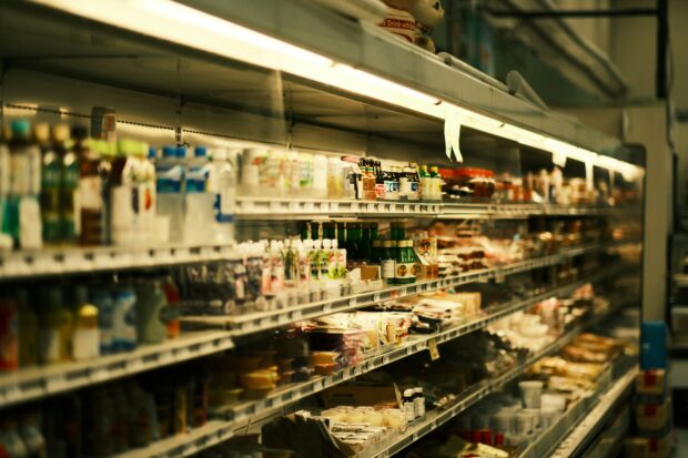 A grocery store fridge filled with lots of food and drinks. Photo by Jose Fabula on Unsplash.
